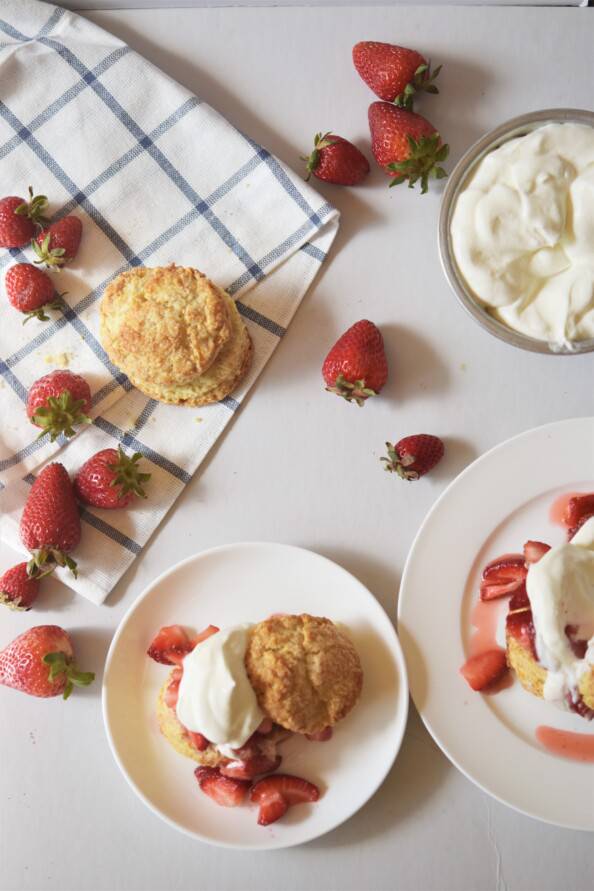 two plates of strawberry shortcake with a side of whipped cream