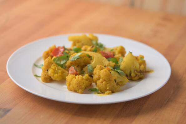 Cauliflower cooked in curry spices on a white plate