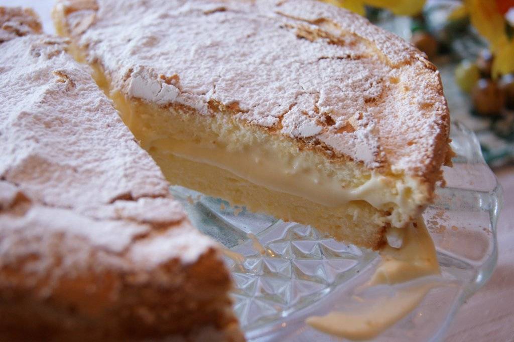 close up of gluten-free lemon sponge cake with lemon filling on a glass cake stand