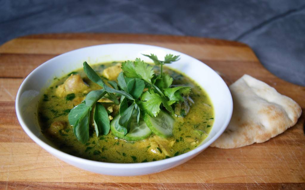 chicken in fenugreek sauce in a while bowl on a cutting board