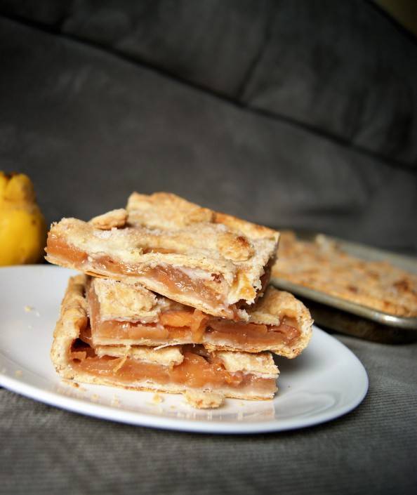 quince slab pie slices stacked on a white plate with a grey background