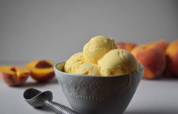 Homemade peach ice cream in a bowl with peaches