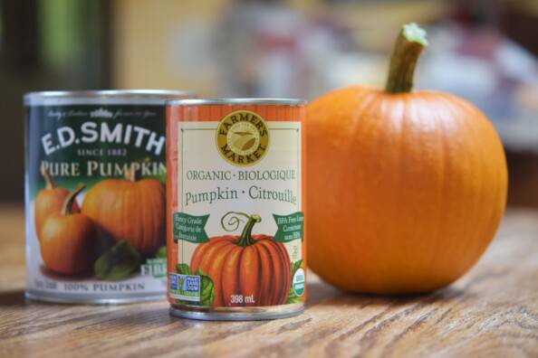 two cans of pumpkin puree and a sugar pumpkin on a wooden table