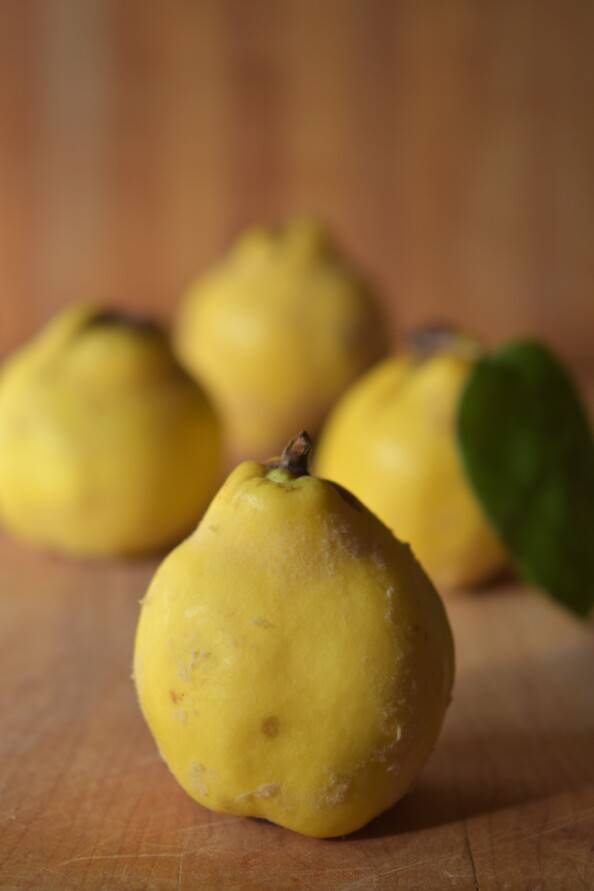 four quince on a wooden cutting board