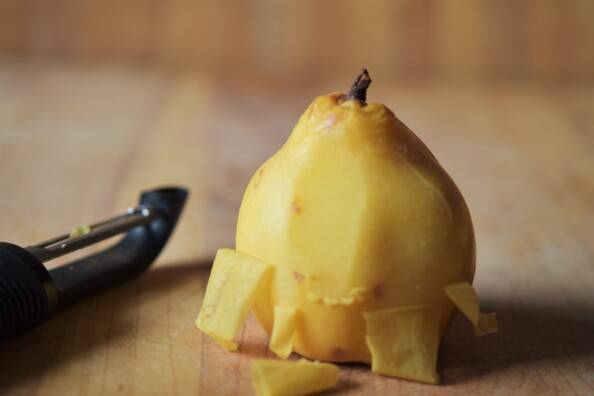 a quince, partially peeled, with black peeler